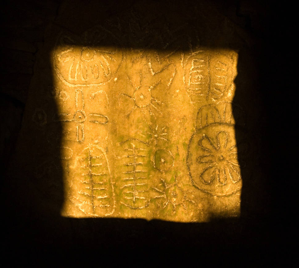 Sunlight illuminates the carved stone inside Cairn T