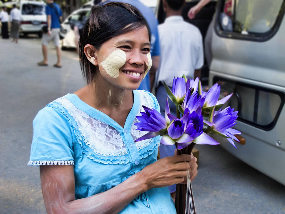 A pregnant woman sells water-lily blooms for offerings outside Kuthodaw Pagoda