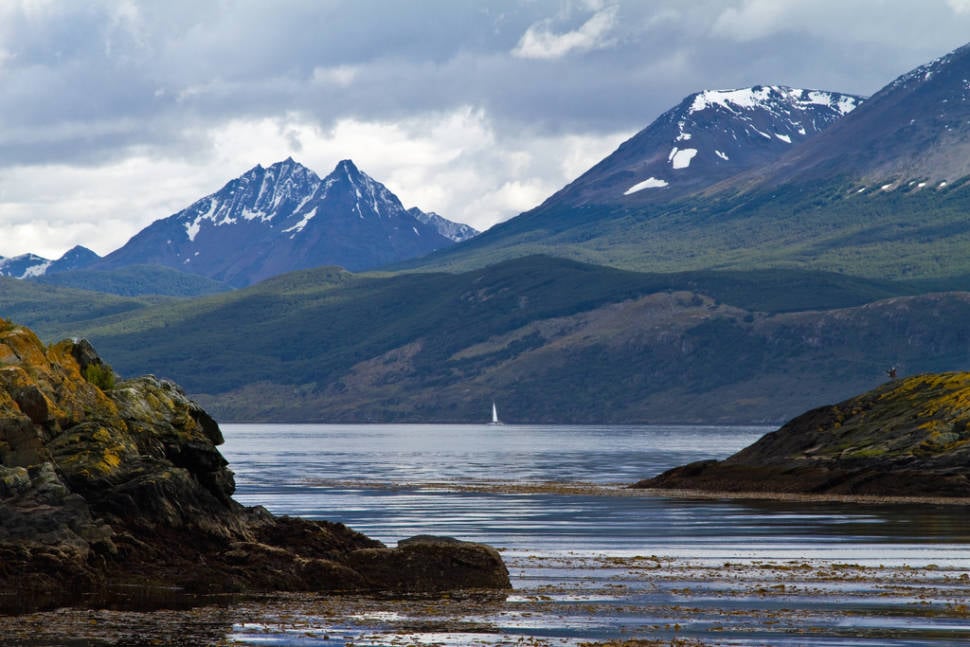 A lone sailboat in the distance is a very small thing against the backdrop of the Andes. Beagle Channel near Ushuaia, Argentina