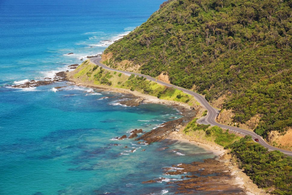 A little red car (spot it?) navigates the bends of the Great Ocean Road just past the town of Lorne