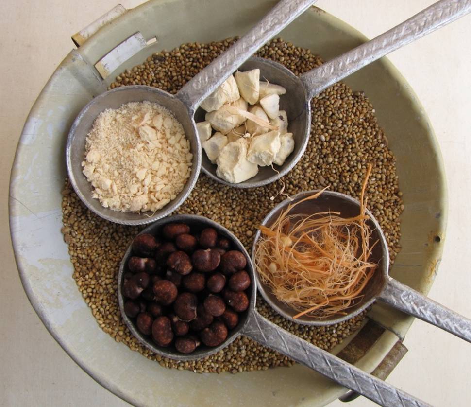 The dry, mature baobab fruit pulp chunks are shown compared to the three elements that comprise it: a white, opaque powdery edible pulp separated from pinkish fibers and brown baobab seeds.